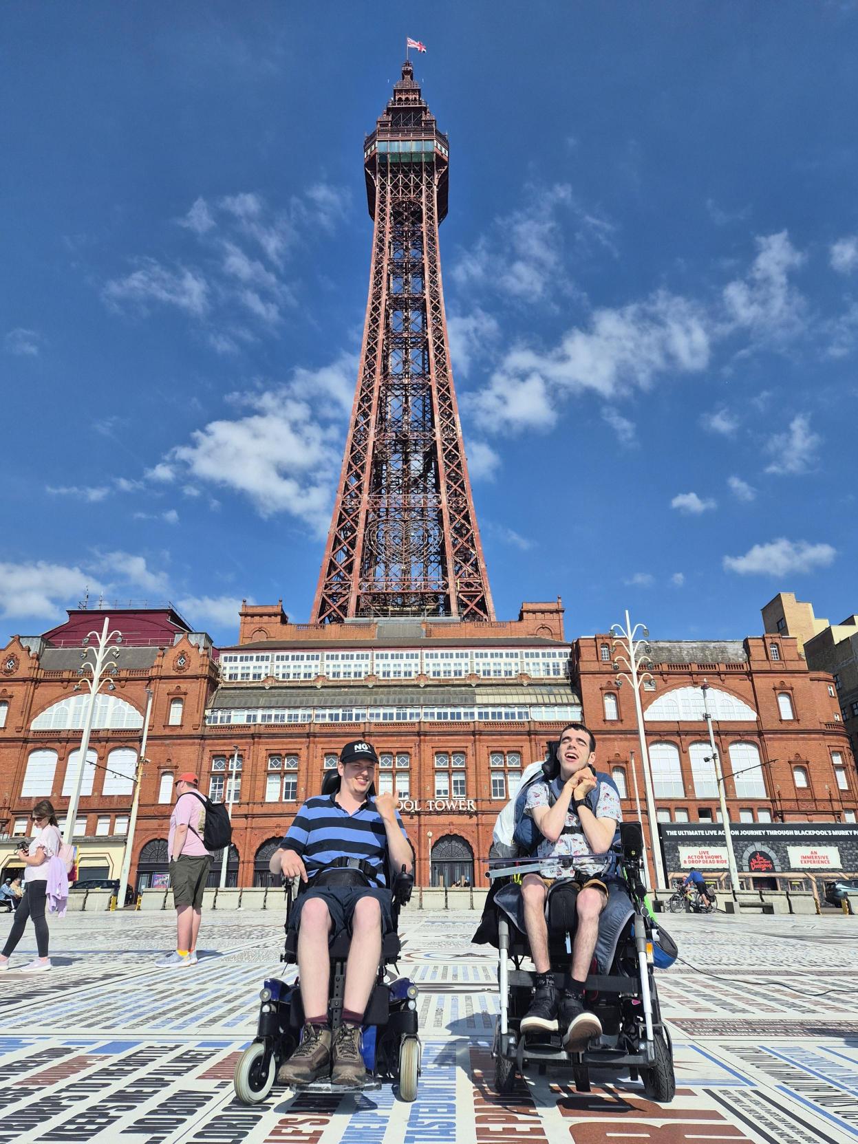 Two men in wheelchairs in front of the Blackpool tower 