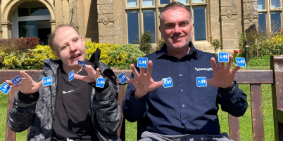 Sam and Matt smiling holding up new blue badge campaign labels