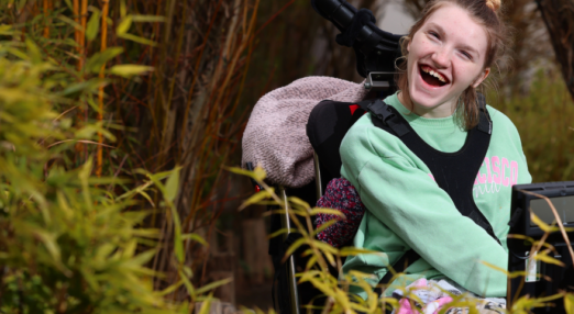 Hannah smiling with flowers and plants in the foreground