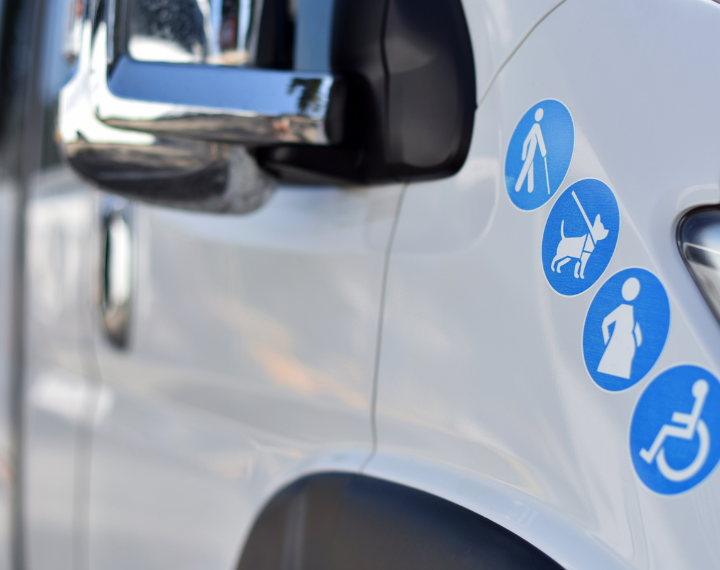 Photo of minibus with blue stickers featuring blind people, dog walkers, pregnant women and disabled people