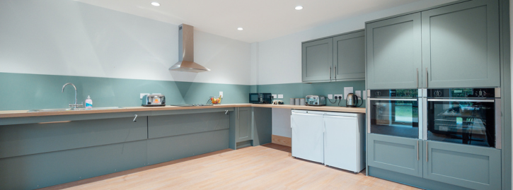 Accessible kitchen featuring ovens, fridge, accessible worktops