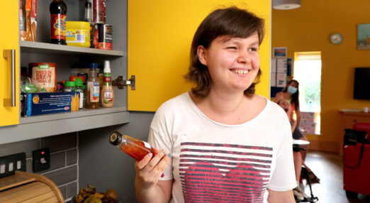 Female student turning towards the camera as she takes an item of food out of the cupboard