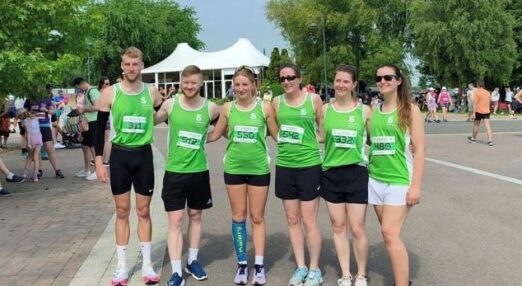 Group of male and female runners standing in a line wearing National Star running vests