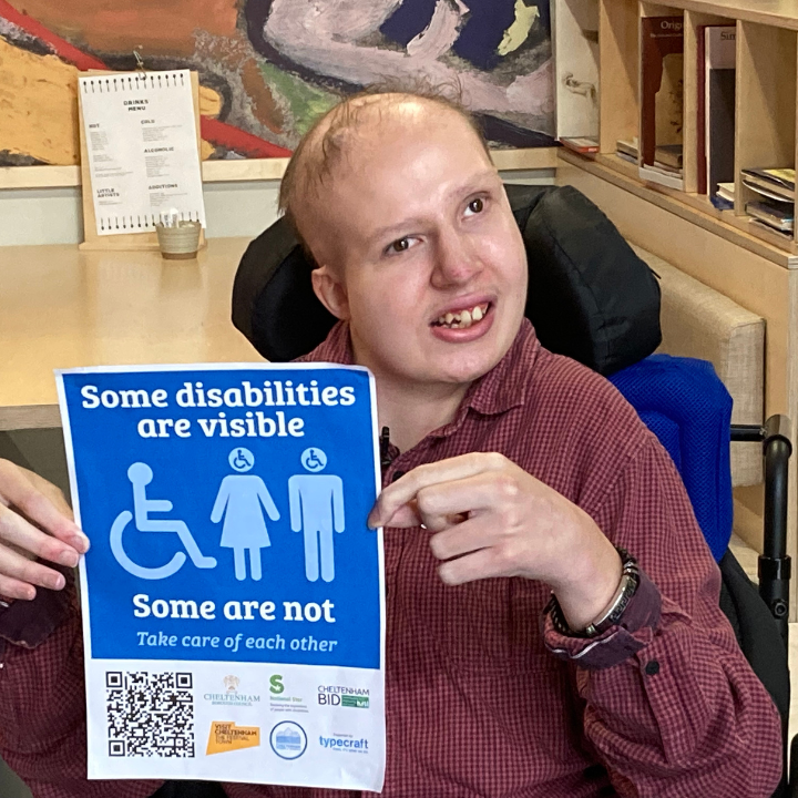 Sam holding up blue badge disability campaign poster