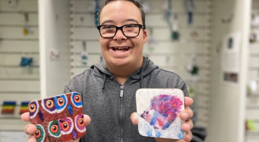 Joshie smiling holding up coasters