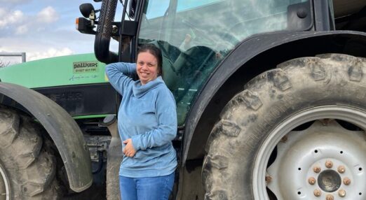 Vanessa smiling in front of the tractor at Wessington Court Farm