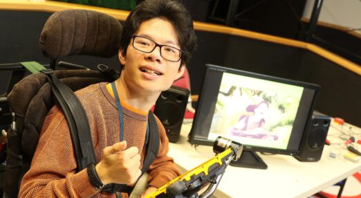 Leo smiling using his AAC device